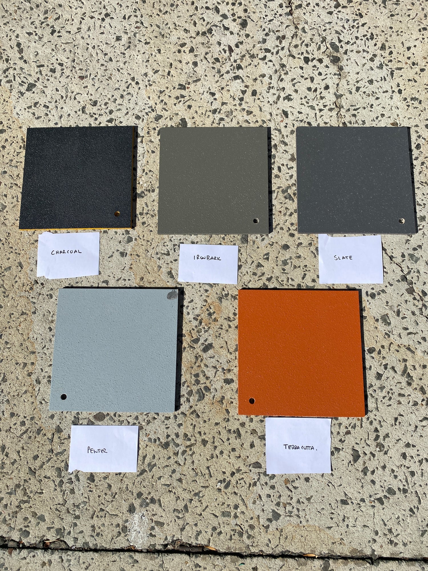 Color swatches of Norglass Paving Paint on a textured concrete surface